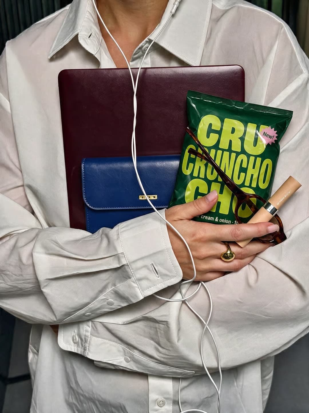 A woman holds a bag of Cru Cruncho chips with a laptop and headphones